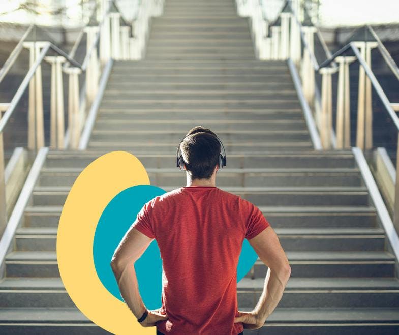 A man wearing earphone standing in front of the stairs